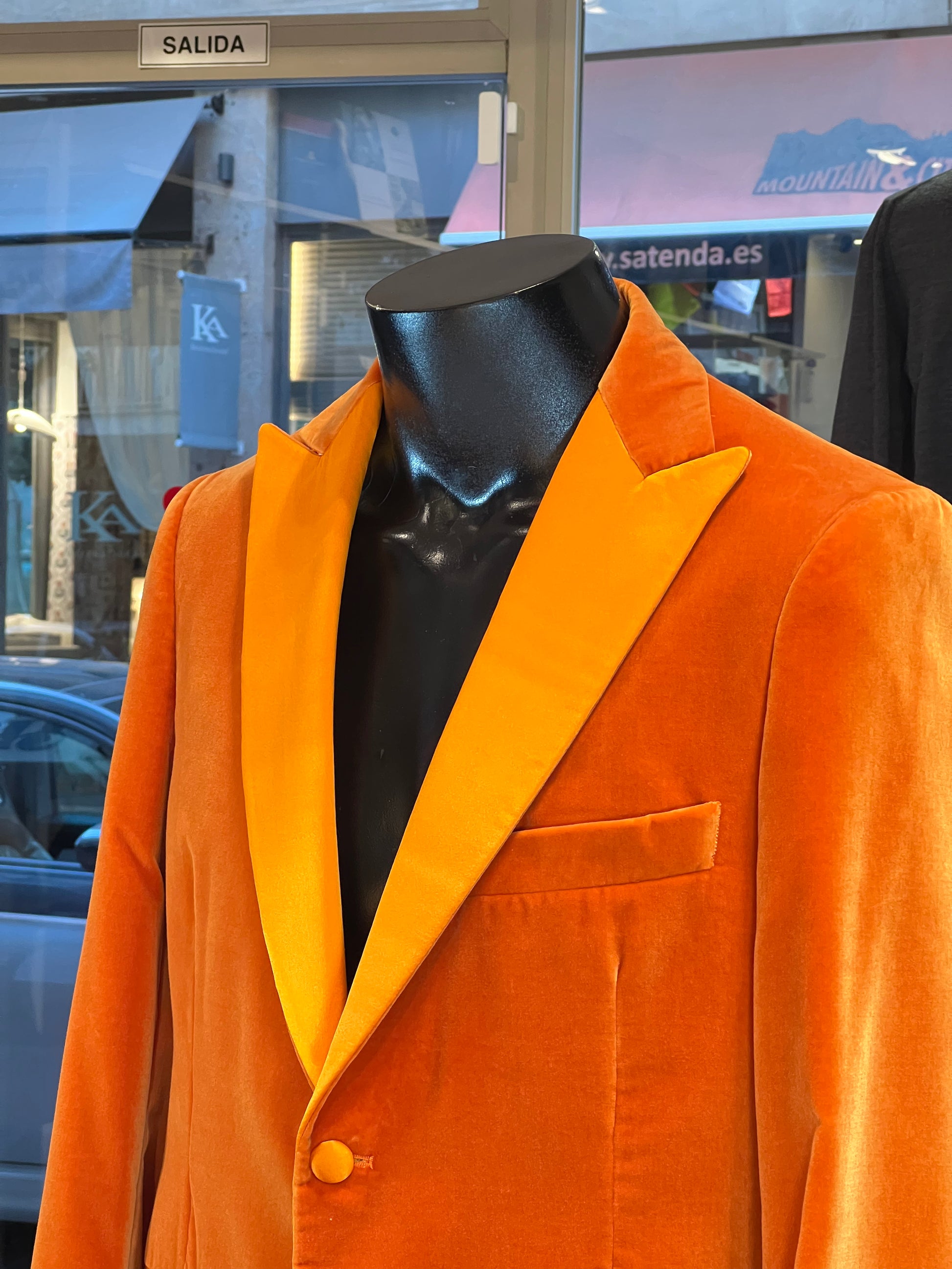 Luxury orange velvet blazer by John Blond, handcrafted with Carnet Como fabric, featuring contrasting amber peak lapels, covered buttons, and ivory satin lining — elegant statement jacket for formal or evening wear.